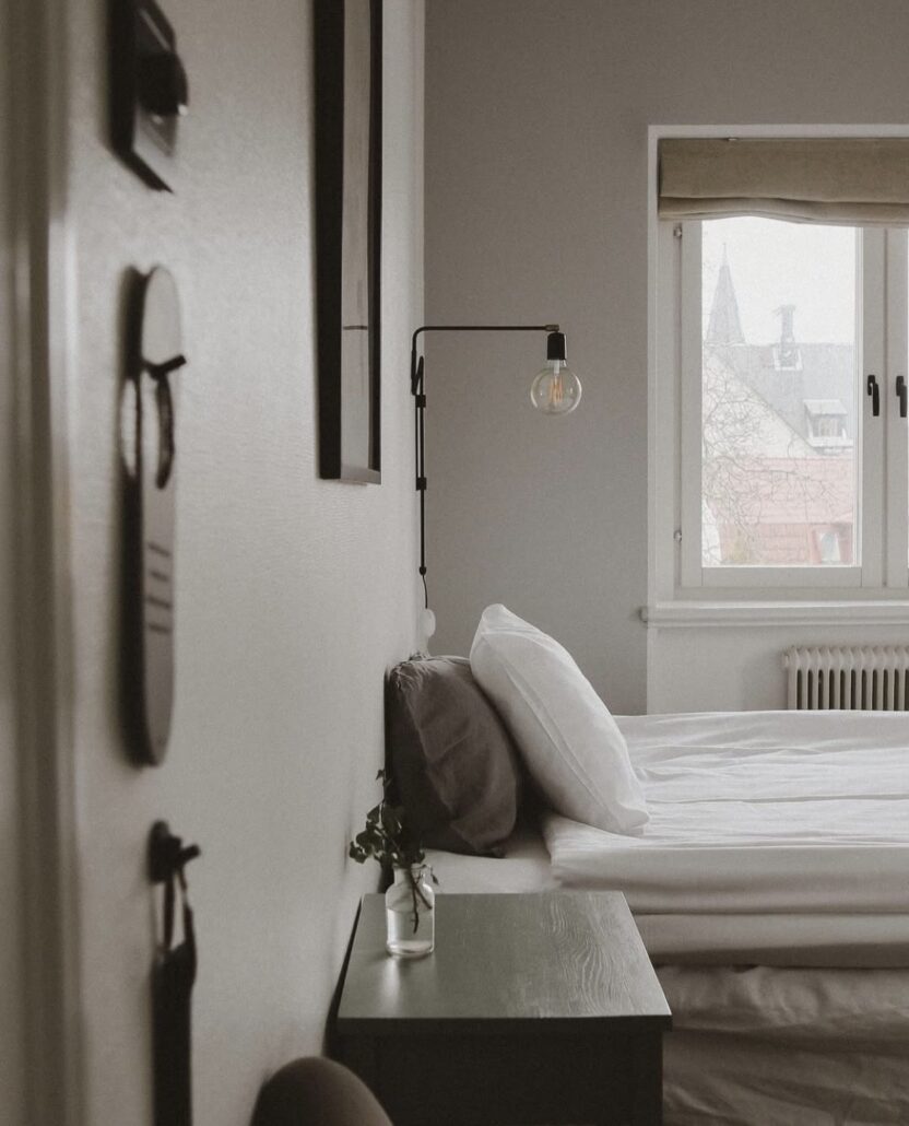 Bild på ett av Villa Borgens rum, visar en dubbelsäng, sängbord och en vägghängd lampa.